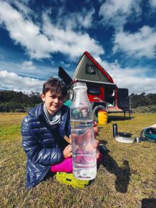 a young boy is holding a bottle in a field at BAGUAL TRAILER in Ushuaia
