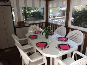 a table with white chairs and a white table with pink napkins at Mobilhome 3 chambres tout confort, proche de la plage in Saint-Brevin-les-Pins
