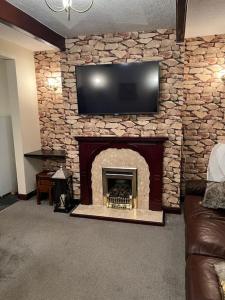 a living room with a stone fireplace with a flat screen tv at Park cottage High Crompton in Shaw