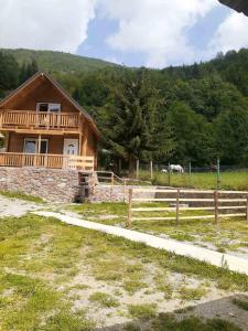 una casa in legno con un cavallo in un campo di Villas Meti Rugove a Pejë