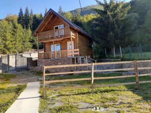 una cabaña de madera con una valla delante en Villas Meti Rugove, en Peje