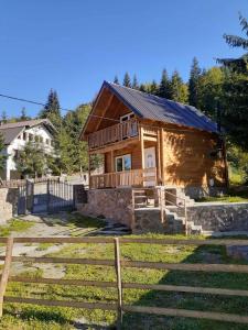 Cabaña de madera con porche y valla en Villas Meti Rugove en Peje