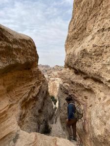 a man is walking through a canyon at 7 Caves Hotel in Al Jāyah