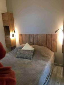 a bedroom with a bed with a wooden headboard and two lights at Gîte D Day in Carentan