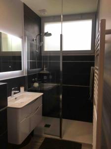 a bathroom with a glass shower and a sink at Gîte D Day in Carentan