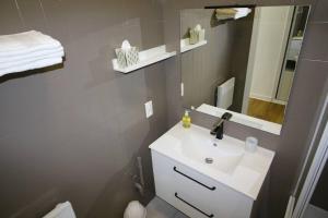 La salle de bains est pourvue d'un lavabo blanc et d'un miroir. dans l'établissement Quartier Historique du Château bel appt meublé, à Pau