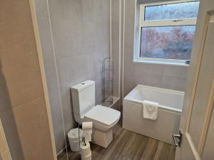 a bathroom with a toilet and a tub and a window at Grange Villa Amethyst 3 Bed House in Chester-le-Street