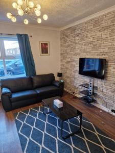 ein Wohnzimmer mit einem schwarzen Ledersofa und einem TV in der Unterkunft Chester Le Street's Diamond 3 Bed House in Chester-le-Street