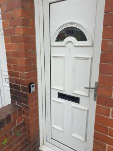 a white door with a clock on it next to a brick building at South Shield's Emerald 2 Bed Apartment in South Shields