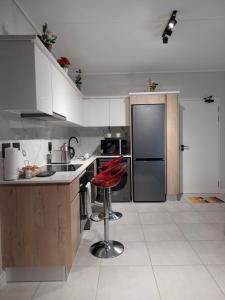 cocina con nevera y taburete rojo en Craiden Holiday Apartment at The Blyde Crystal Lagoon 2 bedrooms en Pretoria