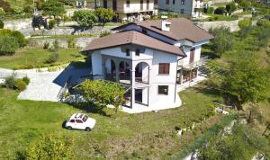 une petite maison avec une voiture garée dans l'herbe dans l'établissement Villa Domus Bianca Mountain Lake Iseo Hospitality, à Costa Volpino
