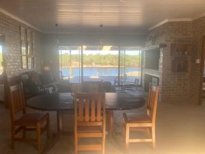 a dining room with a table and chairs with a view of the water at De Poort Cottage in Bredasdorp