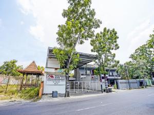 un edificio al lado de una calle con árboles en OYO 92124 Raya Permai Homestay Syariah en Pamekasan