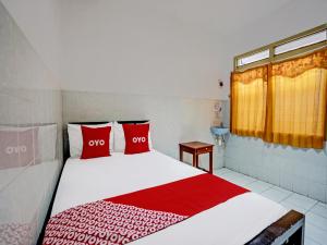 1 dormitorio con 1 cama con almohadas rojas en OYO 92124 Raya Permai Homestay Syariah en Pamekasan