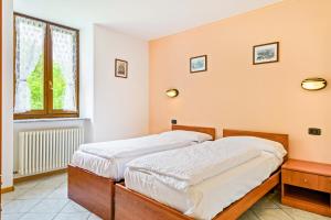 two twin beds in a room with a window at Casa Elena in Ledro