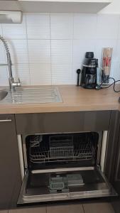 an open dishwasher in a kitchen with a sink at Les soleiades in Béziers