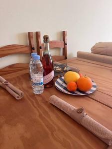 - une bouteille de vin et des fruits sur une table en bois dans l'établissement Apartament na Cyprze, à Peyia