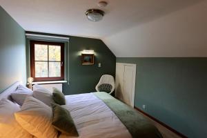 een slaapkamer met een groot bed met een groene muur bij La colline aux hirondelles in La-Roche-en-Ardenne
