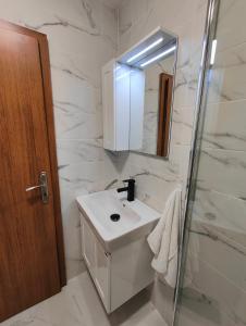 a white bathroom with a sink and a mirror at Апартамент РАЯ in Chepelare
