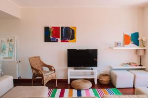 a living room with a flat screen tv and a chair at Just like Home - Number 8 em Quinta das Mineirinhas in Vila Nova de Cerveira