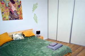 a bedroom with a green bed with a painting on the wall at Apartament Gustav in Zawiercie