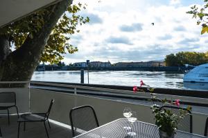 einen Balkon mit einem Tisch und Stühlen sowie Flussblick in der Unterkunft La Bâtie - Terrasse avec Vue imprenable sur le Rhône, 3 chambres, 3 salles de bain in Tain-lʼHermitage