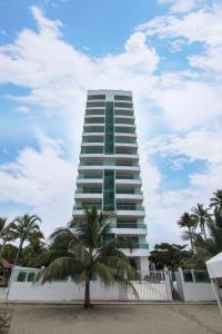 un edificio alto con una palmera delante de él en Magico Apartamento Frente al Mar 3 Habitaciones CV41, en Coveñas
