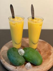 two glasses of orange juice and two pears on a plate at Pearl's Homestay Matale in Matale