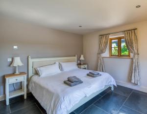 een slaapkamer met een bed met witte lakens en een raam bij Putsborough Manor 3 Self Catering Cottages with Beach a short walk, dog friendly all year, On site Tennis, Play Area, Paddock, Spa baths, BBQ, Private Gardens, Superfast WIFI in Croyde