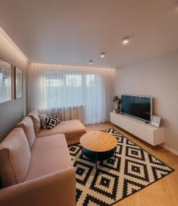 sala de estar con sofá y TV de pantalla plana en Vytautas Park Apartment, en Marijampolė