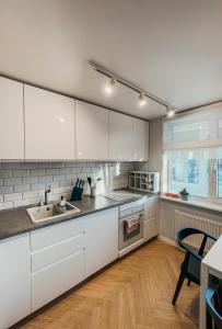 a kitchen with white cabinets and a wooden floor at Vytautas Park Apartment in Marijampolė