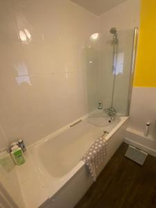 bagno bianco con vasca e doccia di Spacious 1-bed flat in North Kensington a Londra