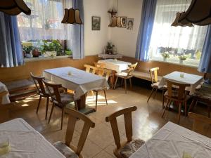 - une salle à manger avec des tables, des chaises et des fenêtres dans l'établissement Haus Grünstein, à Biberwier