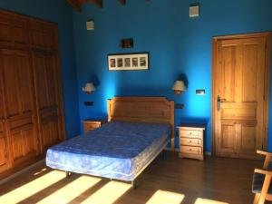 1 dormitorio con cama y pared azul en LA LLANADA en Cangas de Onís
