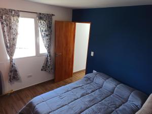 Dormitorio azul con cama y ventana en Dpto Senderos de Andorra - USHUAIA en Ushuaia