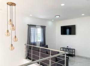 Dieses weiße Zimmer verfügt über ein Bett, einen TV und einen Tisch. in der Unterkunft Villa Ana Luisa - Pool, AC, 3min to Beach, Modern 3BD/3.5BA in La Romana