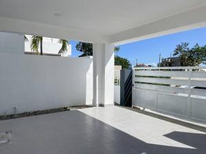 ein weißes Haus mit einer weißen Wand und einer Terrasse in der Unterkunft Villa Ana Luisa - Pool, AC, 3min to Beach, Modern 3BD/3.5BA in La Romana