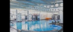 a large swimming pool with blue water in a building at Kens caravan in Abergele