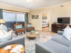 een woonkamer met een bank en stoelen en een televisie bij Sandpiper 205 in Tybee Island
