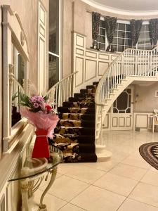 a lobby with a staircase and a vase of flowers on a table at FINN VILLAGE - Loch Lomond Villa B&B with a Hot Tub in Glasgow