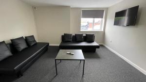 a living room with a black couch and a table at Hosted By Ryan - 1 Bedroom Apartment in Liverpool