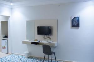 a room with a chair and a tv on a wall at سويتس المقام in Makkah