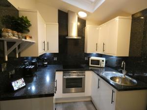 a kitchen with white cabinets and a sink at Lorne View in Oban