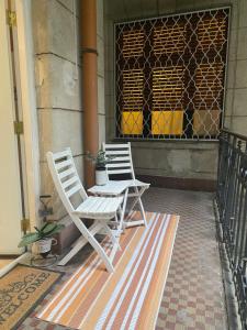 two white chairs sitting on a porch at Jungle Story Apartment by Millenaris Park with Free Parking in Budapest