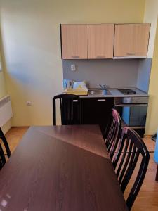 cocina con mesa de madera y sillas y cocina con fregadero en Апартаменти Замъците en Pamporovo
