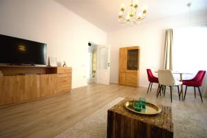 a living room with a tv and a table and chairs at Homey Luxury- entire house, free parking, yard in Cluj-Napoca