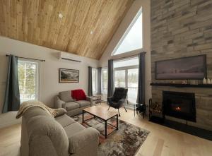 uma sala de estar com um sofá e uma lareira em Chalet Bellevue (Mont-Comi) em Saint-Gabriel