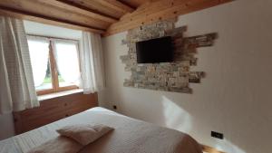 una camera da letto con un letto e una TV a parete di Daniela Apartment a Cortina dʼAmpezzo