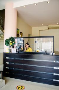 Eine Frau, die hinter einem Tresen steht und auf einem Handy redet. in der Unterkunft Hotel Ceibo Dorado in Portoviejo