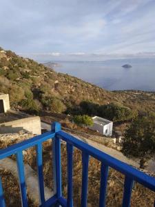 ein blaues Geländer auf einem Hügel mit dem Ozean in der Unterkunft Emporios Traditional Sea View House in Emporeiós